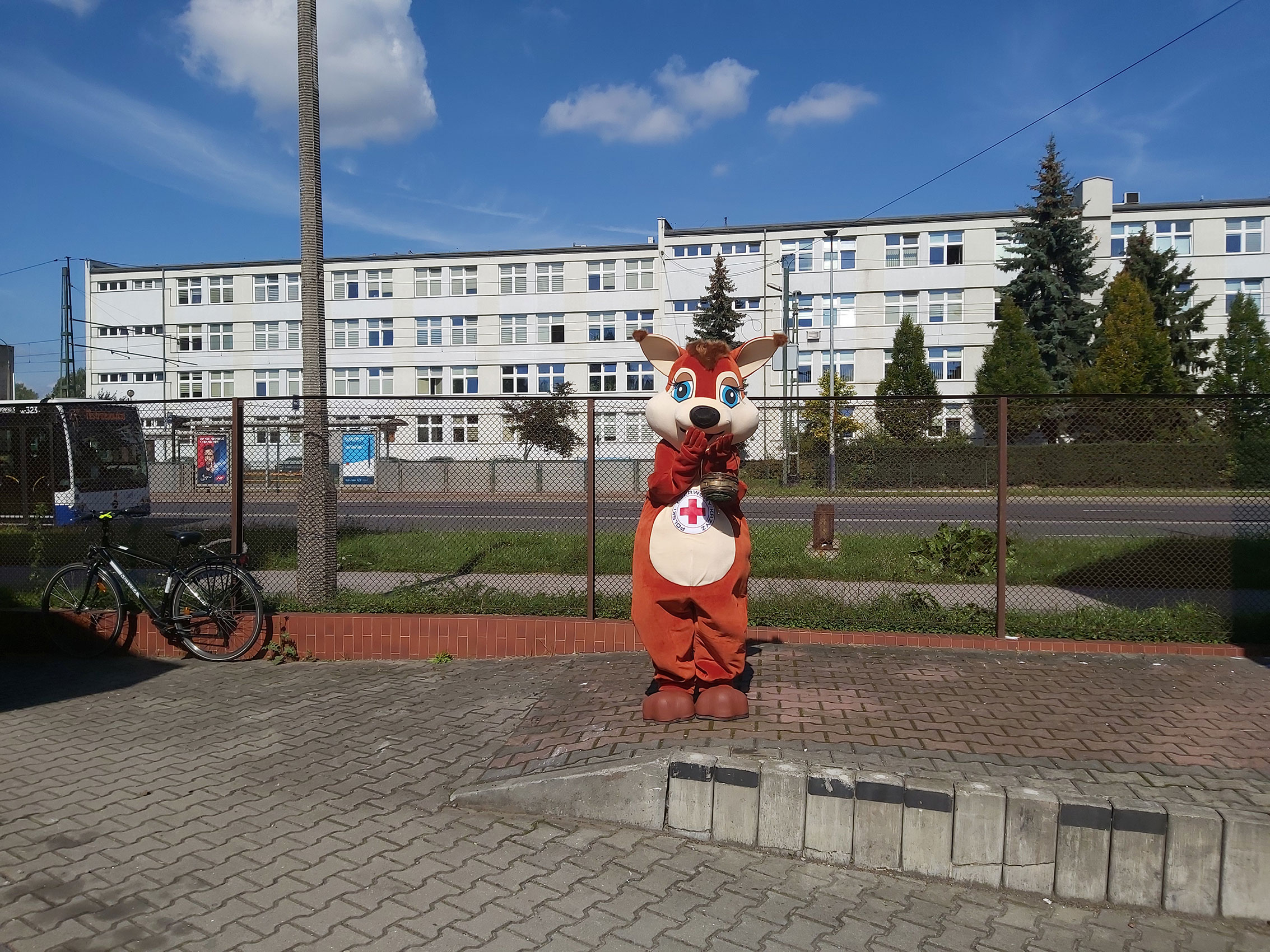 Na fotografii widnieje strój reklamowy w postaci wiewiórki pozujący do zdjęcia przed siedzibą firmy Elabika